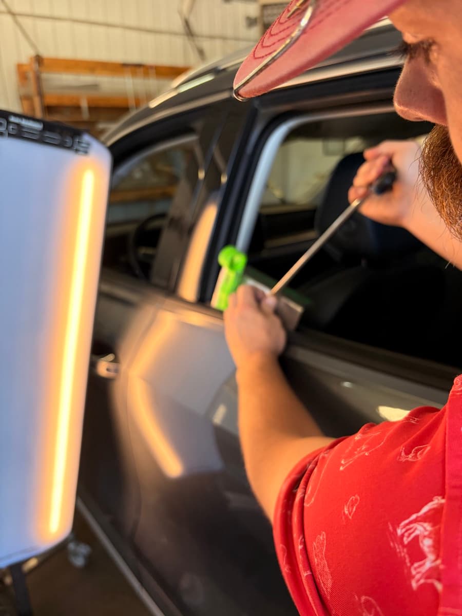Paintless dent repair tool working a hail-damaged panel